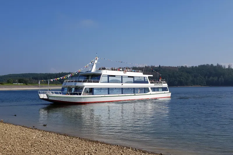 Statek pasażerski MS Sorpesee na jeziorze w pobliżu Sundern, z lasem na drugim brzegu